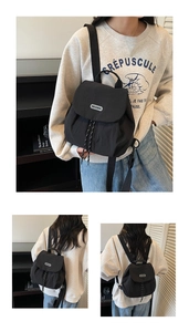 Detail of black nylon backpack with flap closure and adjustable straps on a model