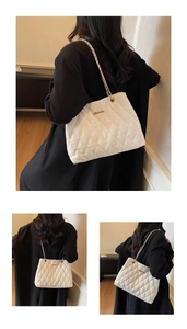 Détail du sac cabas matelassé blanc avec bandoulière en chaîne dorée et logo en métal