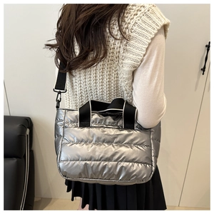 Rear view of model wearing a metallic silver quilted puffer tote bag with black strap