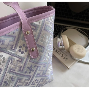 Detail of jacquard tote bag with traditional geometric pattern and metal rivet accents