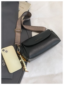 Dettaglio borsa a tracolla vintage nera con tracolla etnica e perle su un completo grigio
