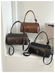 Close-up of three retro square handbags in black, dark brown, and tan leather
