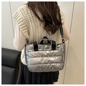 Detail of silver metallic quilted bucket bag with contrast webbed handles and shoulder strap
