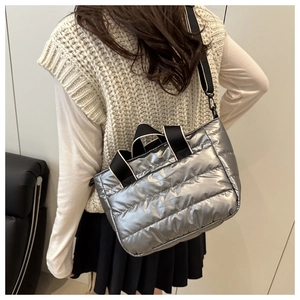 Silver quilted tote bag detail with black nylon straps shown on a model in a modern style