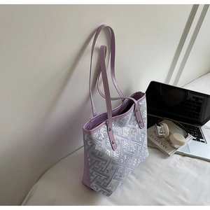 Detail of lavender tote bag with geometric maze pattern next to art book and laptop