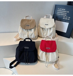 Four colors of mini nylon backpacks with drawstring closure and buckle flaps on display