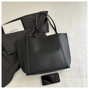 Detail shot of black leather tote bag paired with stylish office outfit and lifestyle items