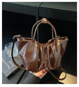 Detailed view of dark brown pleated cloud bag featuring glossy finish and metal hardware
