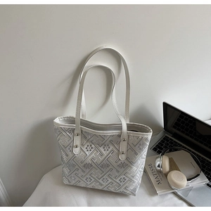 Detail of white jacquard tote bag with geometric embroidery and silver rivet accents