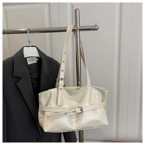 Detail of cream glossy shoulder bag with decorative belt buckle and adjustable silver buckle