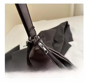 Dettaglio della cerniera argentata sulla borsa a spalla in pelle marrone scuro con texture