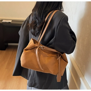 Detail showing the large caramel suede tote bag with slim straps on a female model