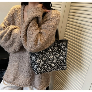 Detail of embroidered tote bag with geometric patterns over a chunky knit sweater