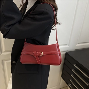 Borsa a spalla rossa minimalista con fibbia a nodo dorata indossata da una modella