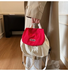 Detail view of the red and cream nylon backpack featuring a drawstring and brand label