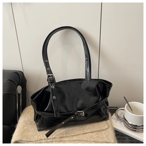 Detailed view of the glossy black patent leather tote with chic metal buckle belt accents