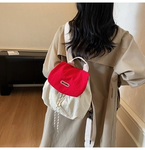 Detail of red and white contrast backpack with logo and drawstring closure shown on model