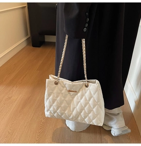 Gros plan du sac cabas matelassé blanc avec chaîne dorée porté par un mannequin