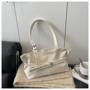 Detail of cream patent leather tote with adjustable belt buckle on soft plush fabric