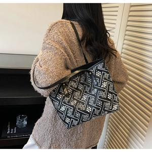 Close-up of black tote bag featuring intricate white ethnic flower embroidery details