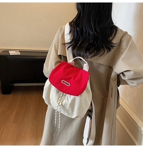 Detailed back view of a nylon drawstring backpack in red and beige on a model