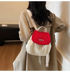 Detail of red and white contrast mini backpack featuring woven handles and cord drawstring