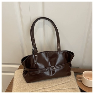 Close-up of glossy dark brown patent leather tote bag with vintage belt buckle hardware