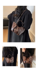 Close-up of pleated patent leather handbag with round top handles and shiny brown finish