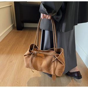 Detail of brown suede tote bag with leather strap buckle in a vintage aesthetic