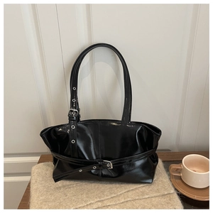 Detail of glossy black patent leather tote bag with silver buckle and belt straps