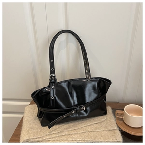 Detail of black patent leather tote bag with silver eyelet belts on soft knit fabric