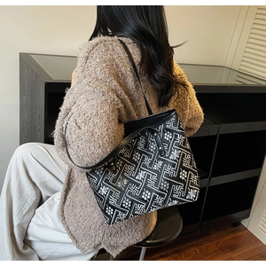 Detailed view of embroidery tote bag worn on shoulder over a beige knit sweater