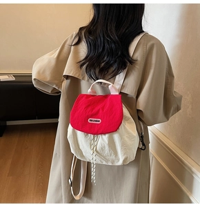 Detail of red and white nylon drawstring backpack with YOU JI BEAR logo on the flap