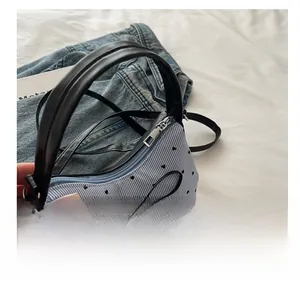 Détail d'un sac à main rayé bleu montrant la fermeture éclair et le nœud décoratif noir