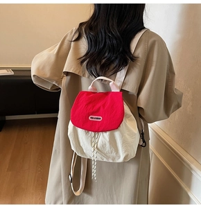 Detail of red and cream nylon backpack featuring brand tag and adjustable drawstrings