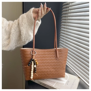 Close-up of brown woven tote bag featuring artisan texture and three-tone bead pendant