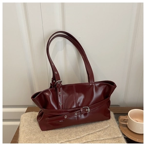 Detail view of burgundy patent leather tote bag with belt buckle and silver hardware