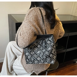 Detail of a black and white patterned tote bag with long shoulder straps worn by a person