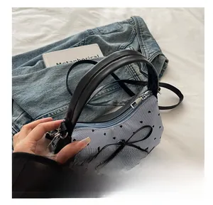 Détail d'un sac à main à rayures bleues avec motifs de cœurs noirs et nœud décor