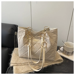 Dettaglio della borsa tote trapuntata beige con catena dorata su coperta di maglia