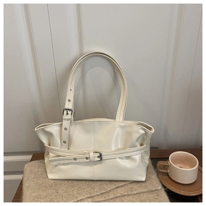 Close-up of cream white patent leather tote bag with buckle strap and silver metal buckle