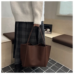 Detailed view of deep brown leather tote bag held by model for stylish daily wear