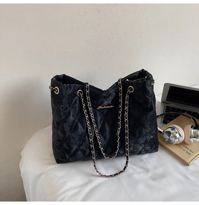Détail d'un grand sac cabas noir matelassé avec bandoulière chaîne sur un bureau