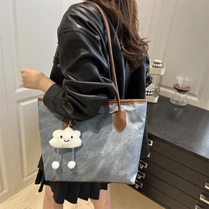 Sac fourre-tout en toile bleue avec anses en cuir et breloque nuage sur l'épaule