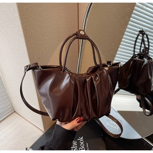 Detailed view of the dark brown ruched patent leather handbag with silver hardware