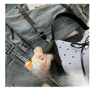 Détail du sac à main bicolore avec motif de cœur, nœud et pendentif lapin en peluche