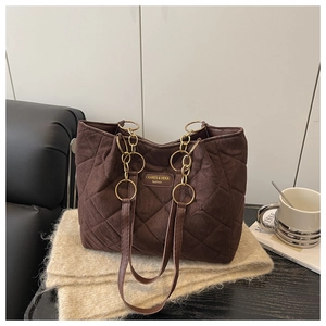 Detail der dunkelbraunen Stepptasche mit Goldkettenriemen und Wildleder-Textur