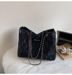 Détail d'un grand sac cabas noir matelassé avec bandoulière chaîne dorée