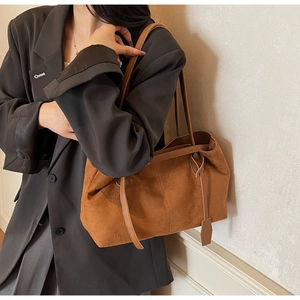 Close-up of brown suede tote bag with slim shoulder straps and fine stitching detail
