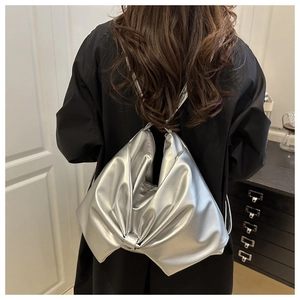 Detailed view of silver metallic bow shoulder bag worn over a black jacket